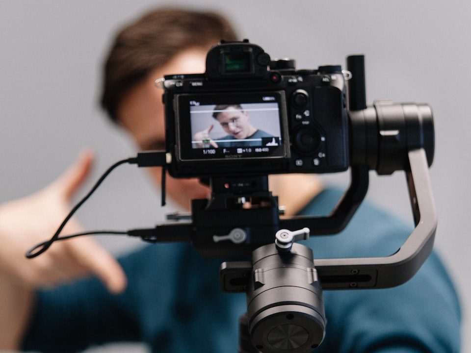 man holding black DSLR camera with stabilizer